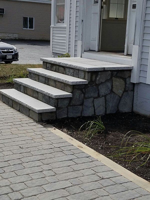 A car is parked in front of a house with stone steps
