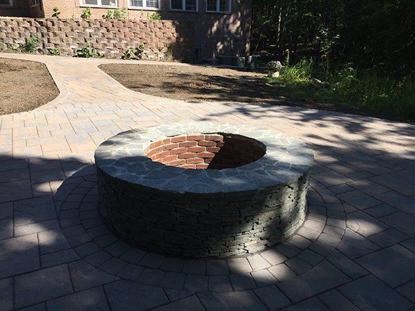 A fire pit is sitting on top of a brick patio.