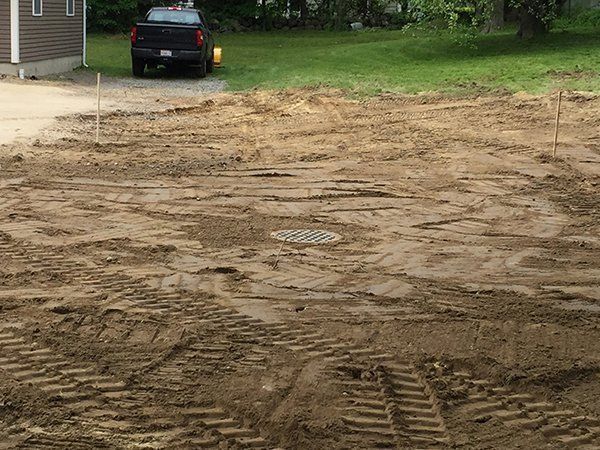 A truck is parked in a dirt lot next to a house.