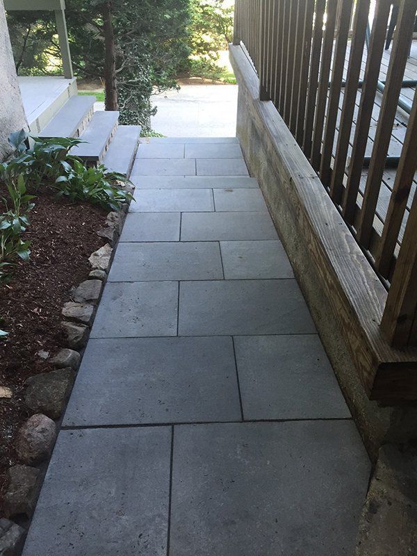 A stone walkway leading to a deck with a wooden railing