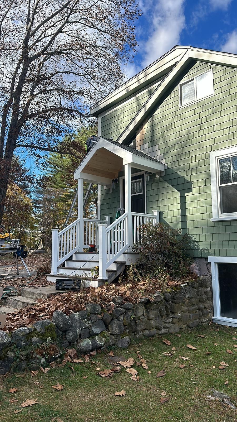 A green house with a white porch and stairs.