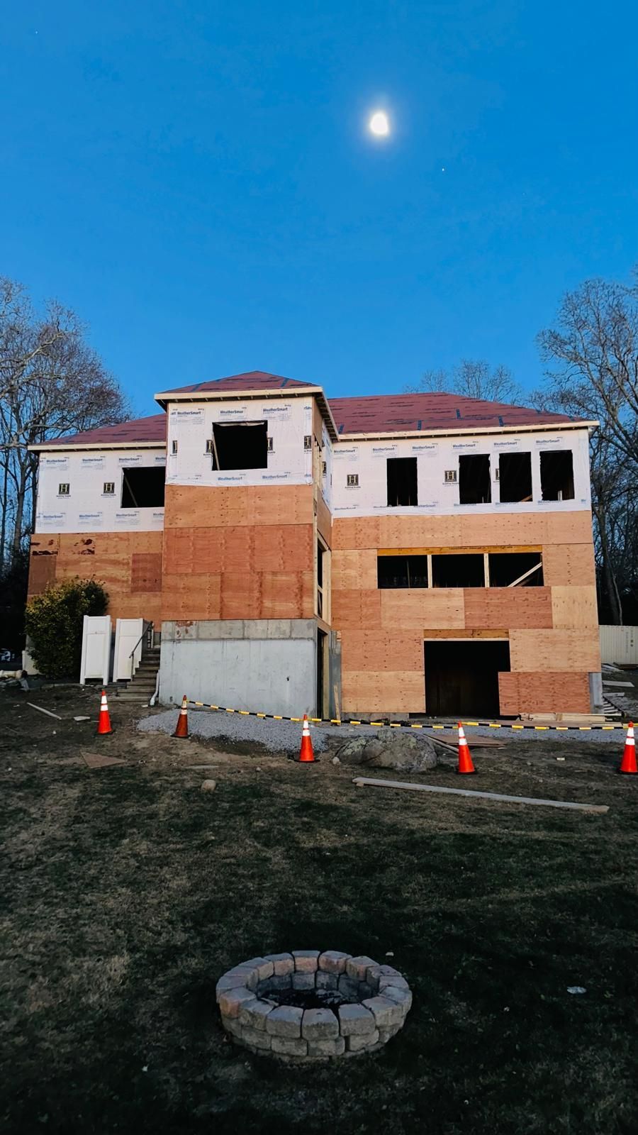 A large house under construction with a fire pit in front of it.