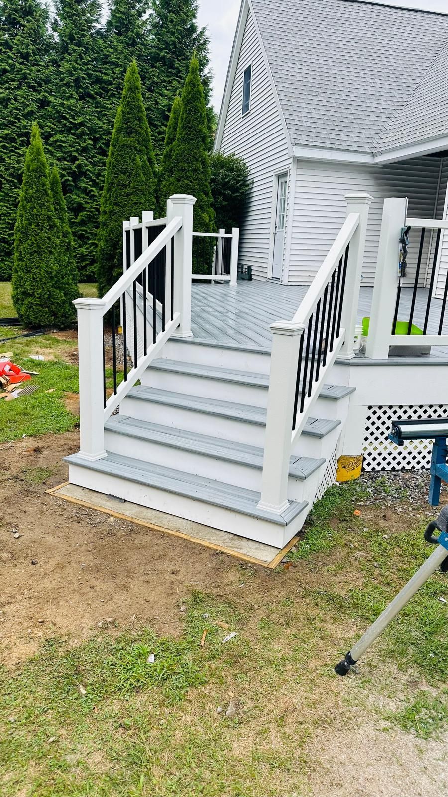 A deck with stairs leading up to it is being built in the backyard of a house.