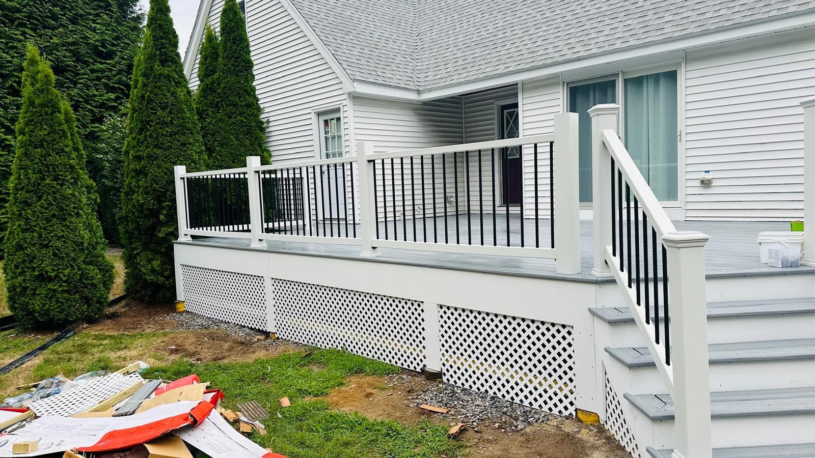 A white house with a deck and stairs in front of it.