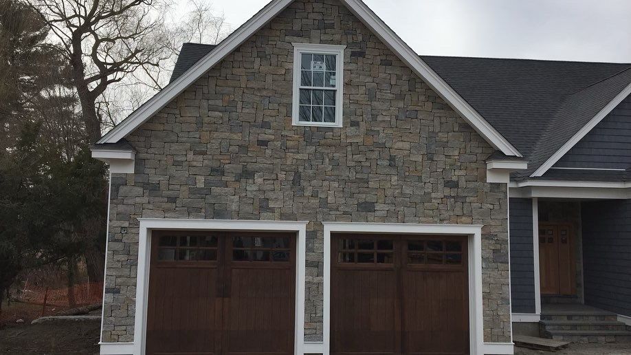 A stone house with two garage doors and a window