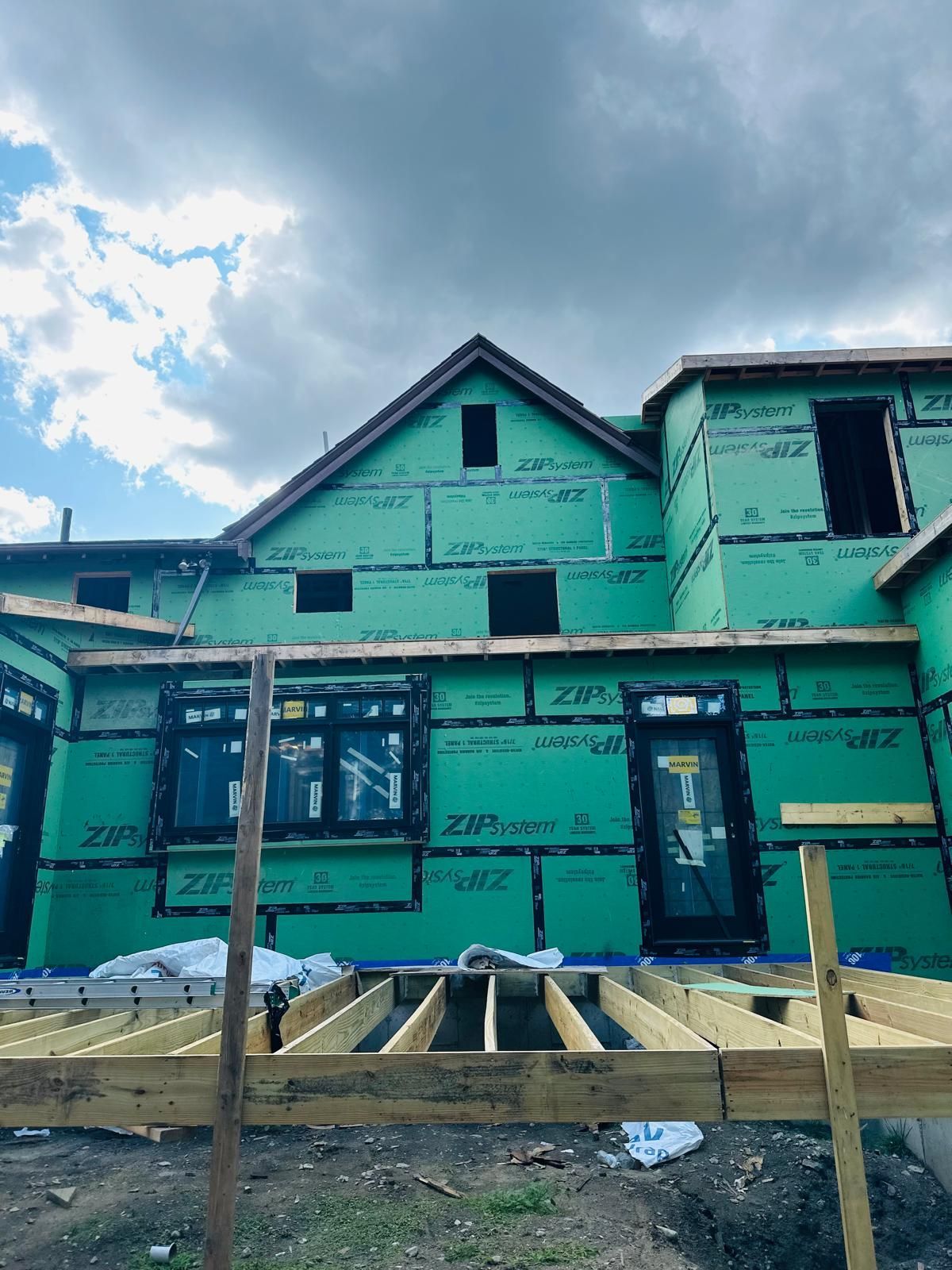 A house is being built with green siding and a wooden deck.