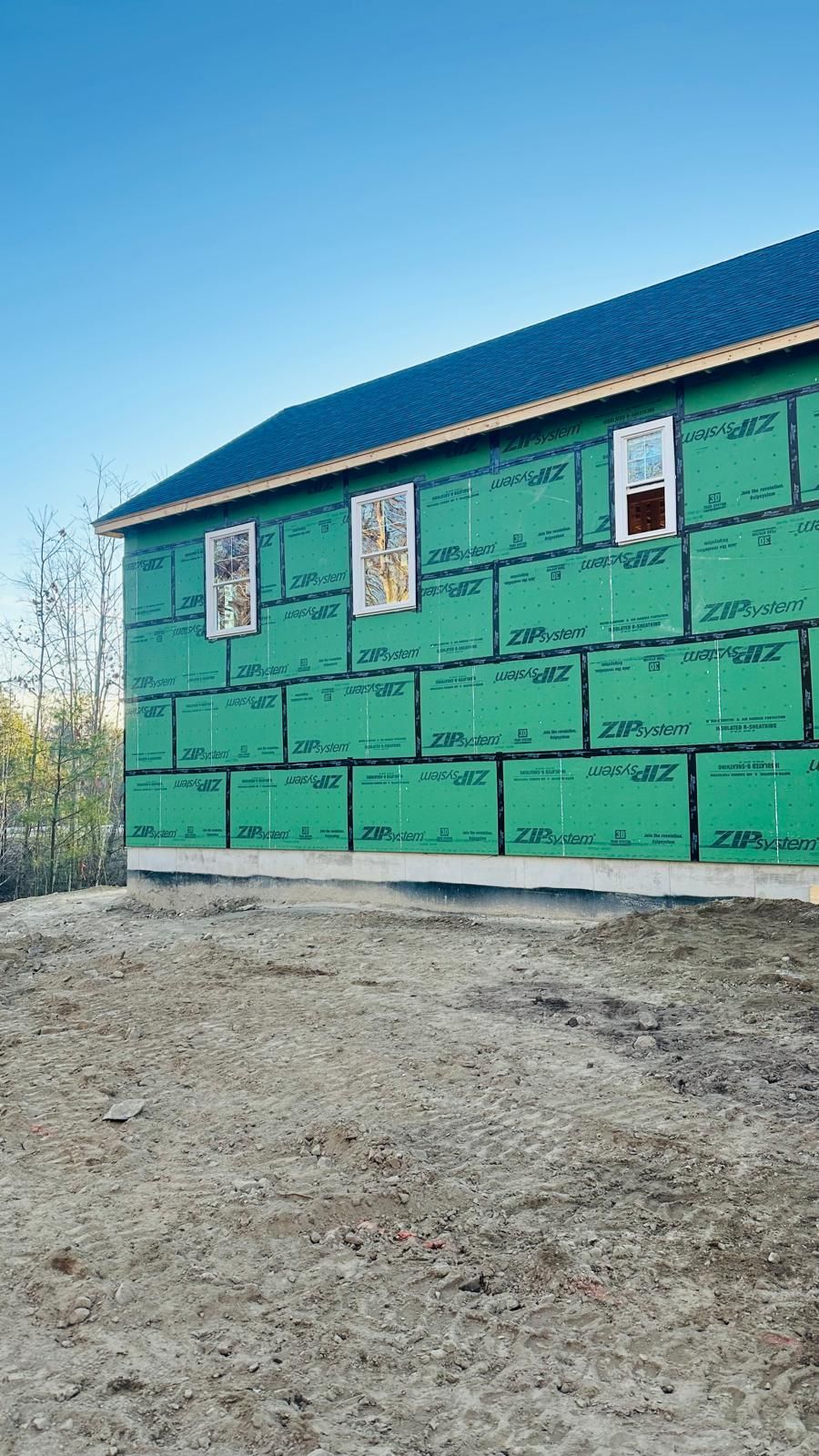 A house is being built with green siding and a blue roof.