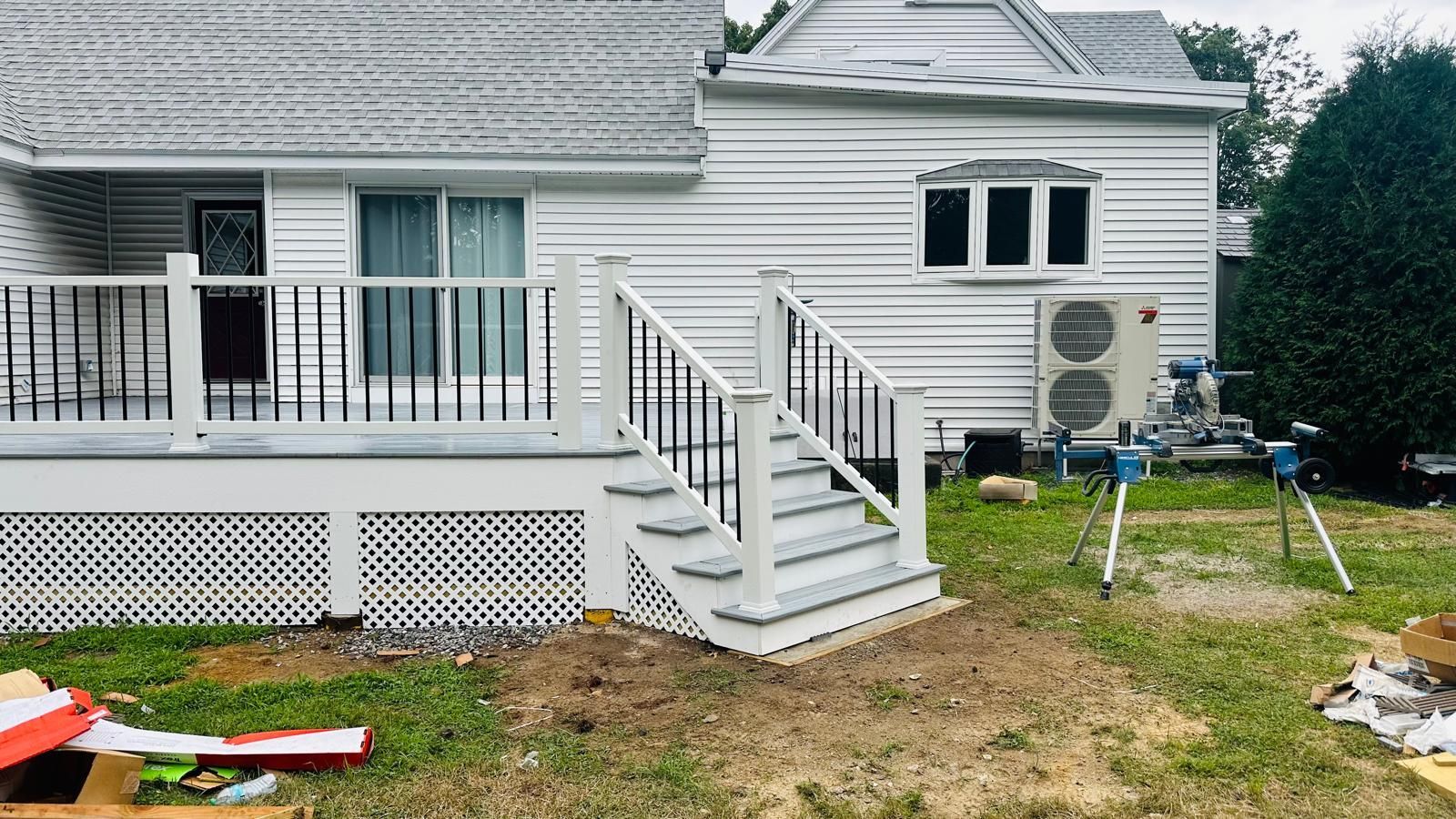 A white house with a white deck and stairs in front of it.