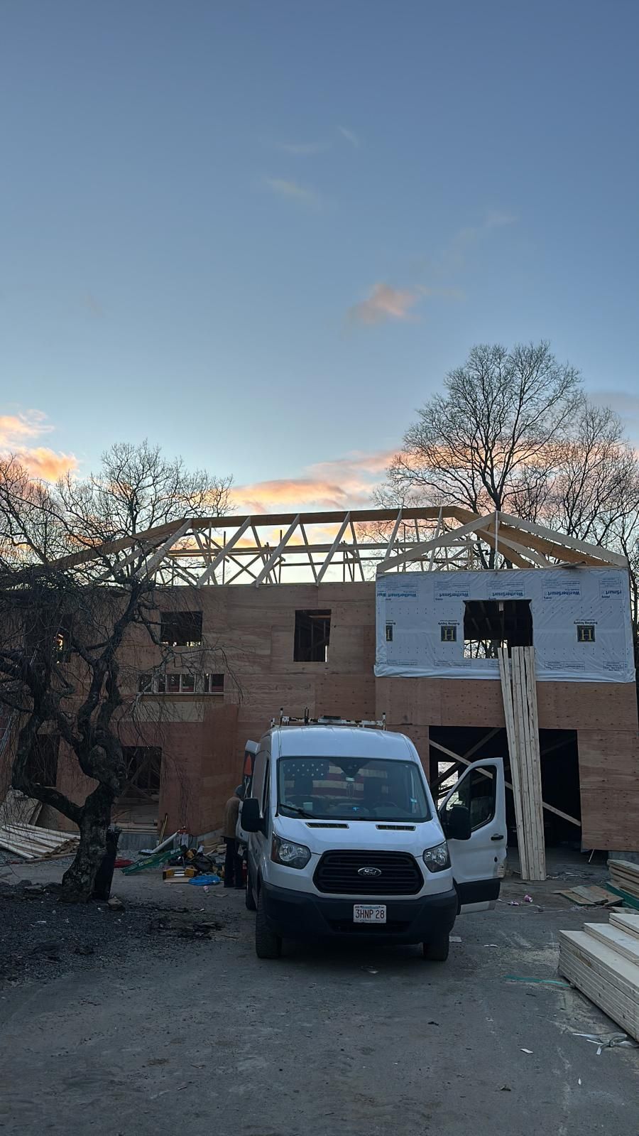 A white van is parked in front of a building under construction.