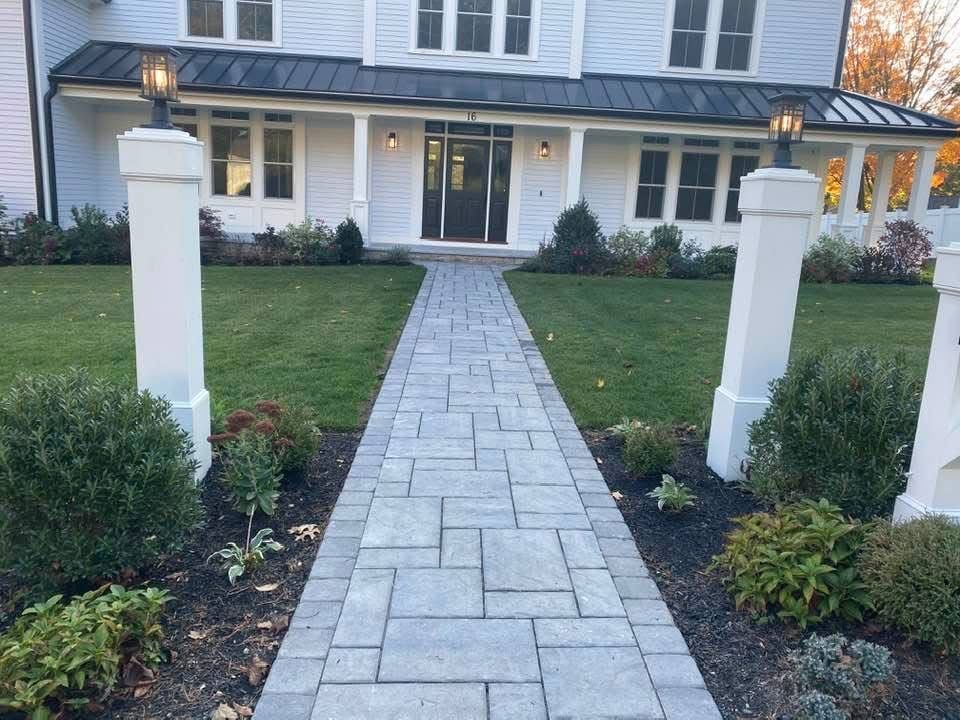 A brick walkway leading to a white house