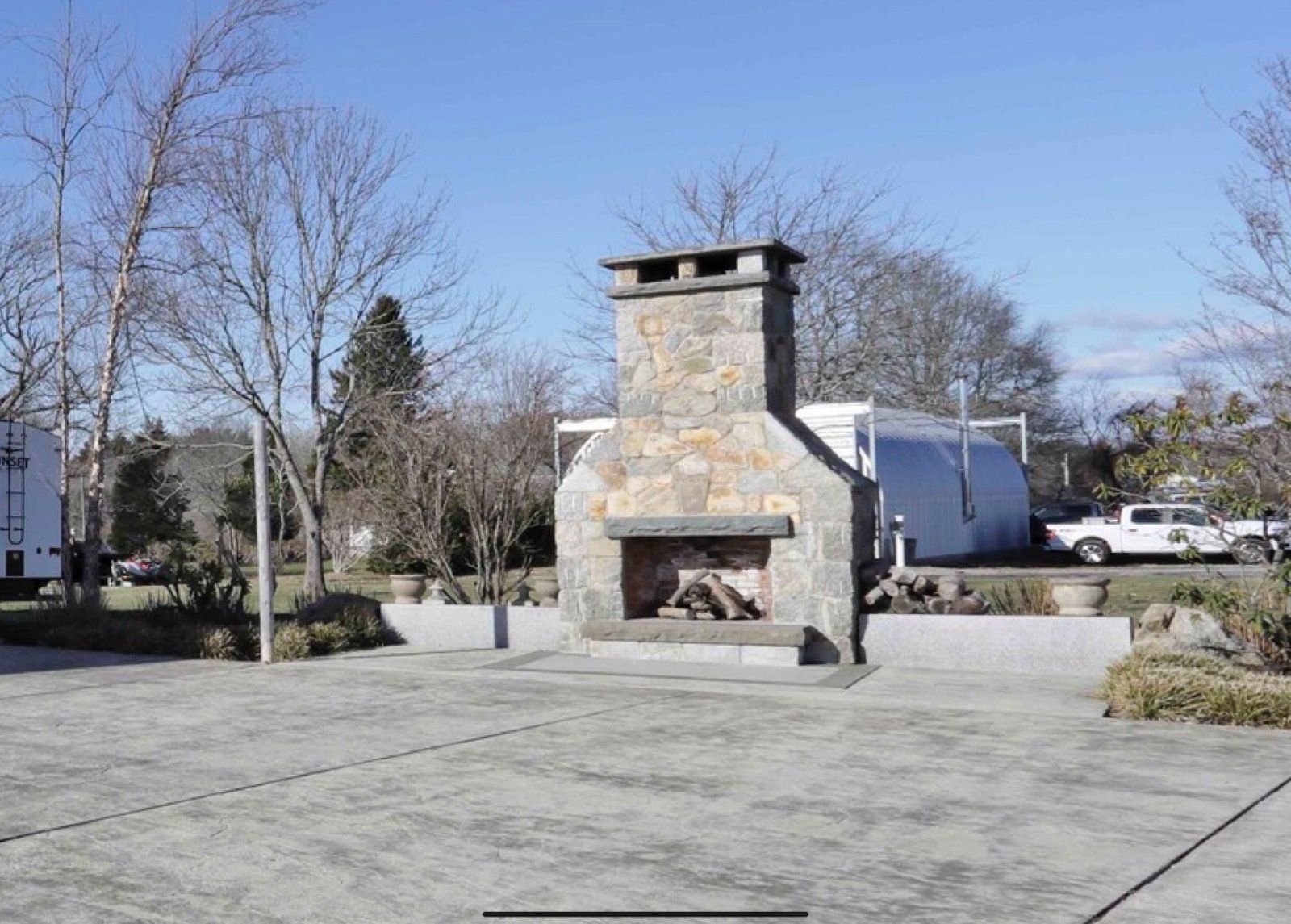 A large stone fireplace is in the middle of a parking lot.