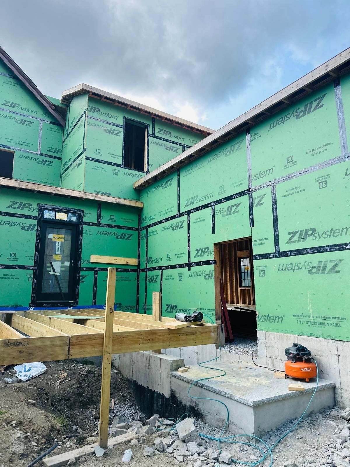 A house is being built with green siding and a wooden deck.