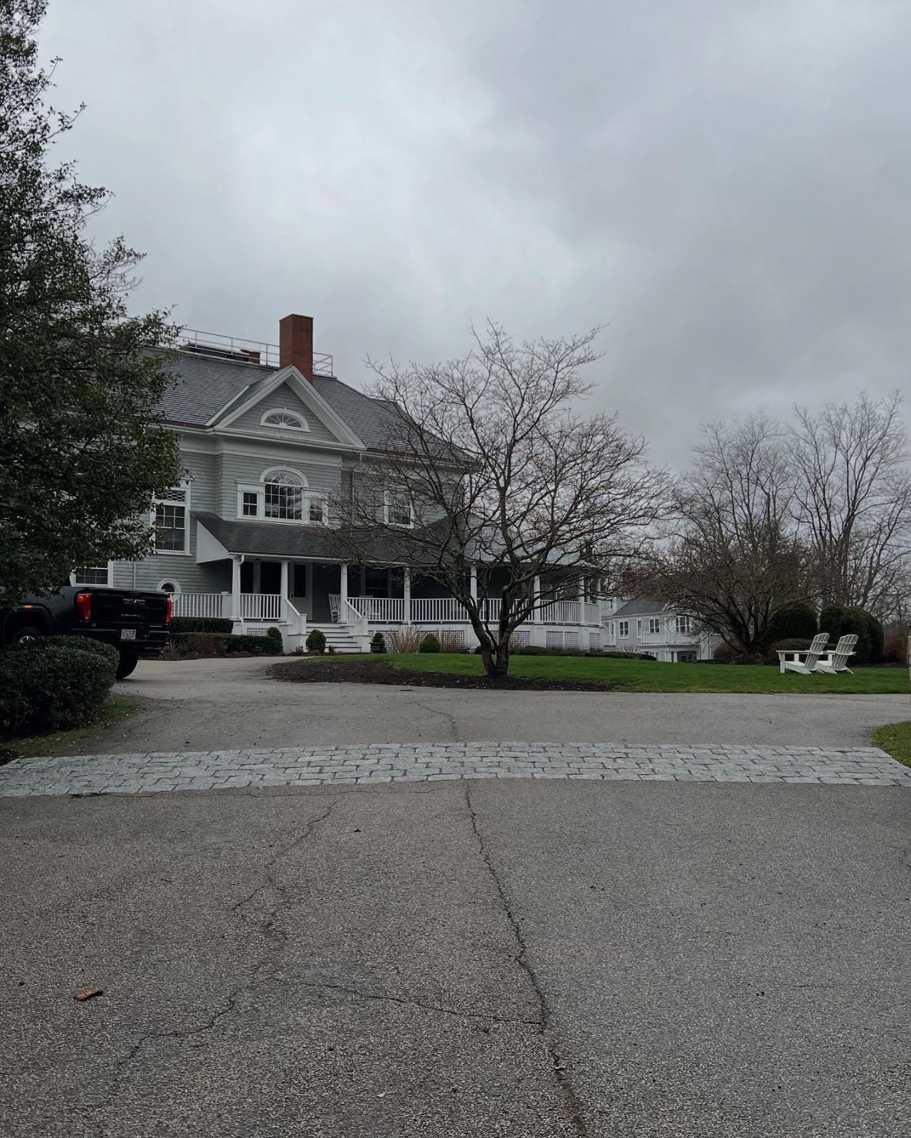 A large white house with a black truck parked in front of it