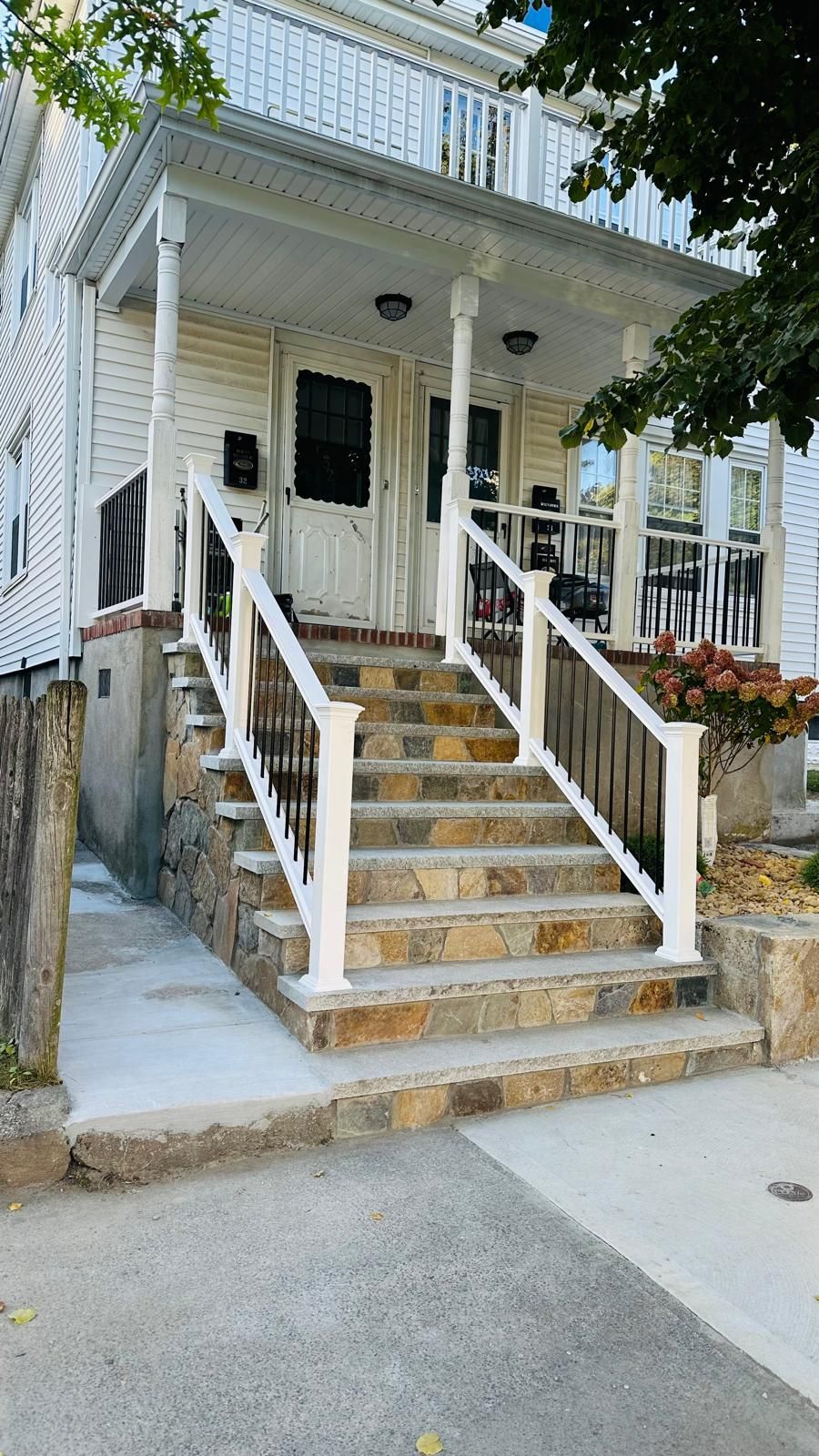 A white house with a porch and stairs leading up to it.