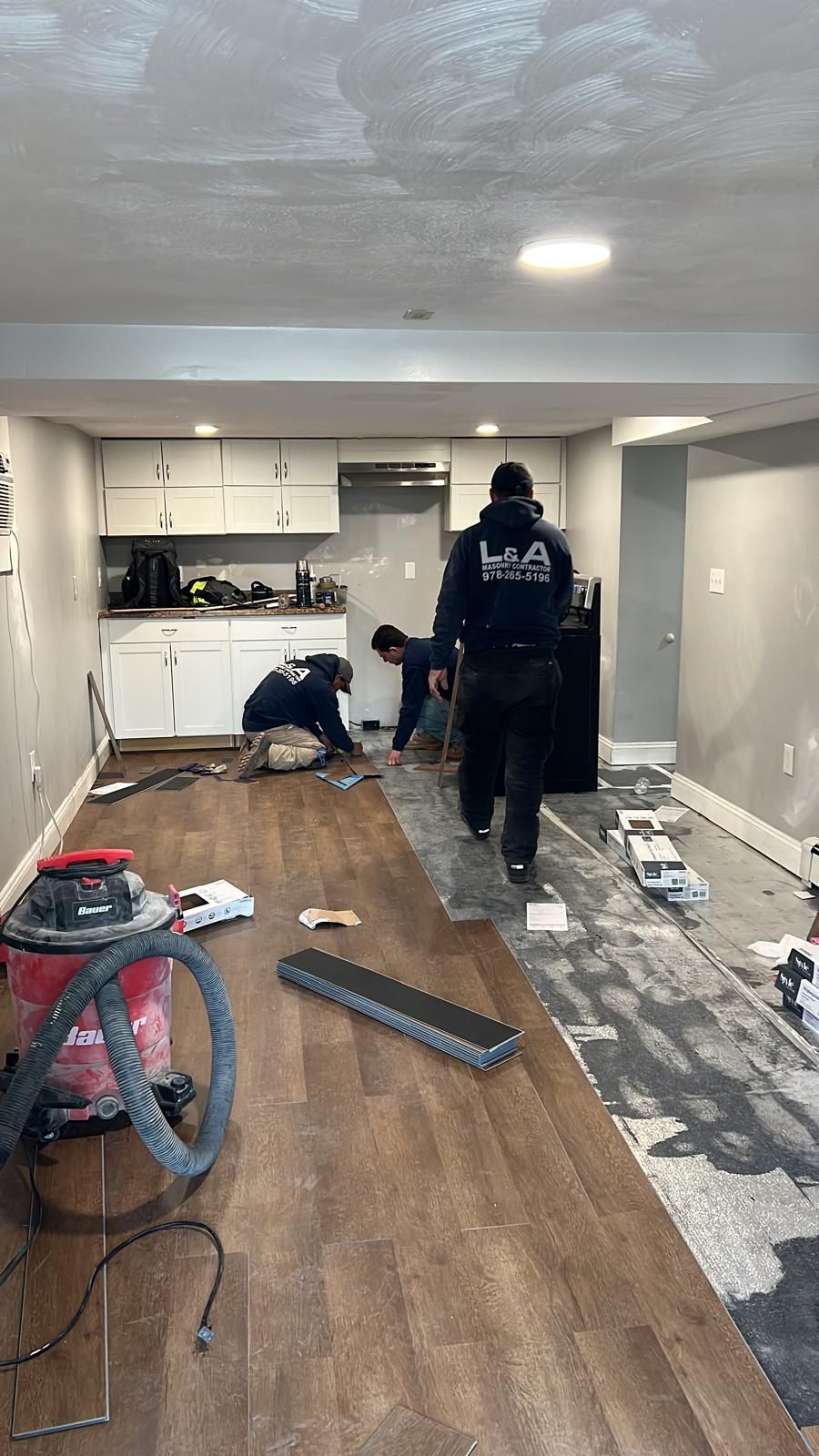 A group of men are installing a wooden floor in a basement.