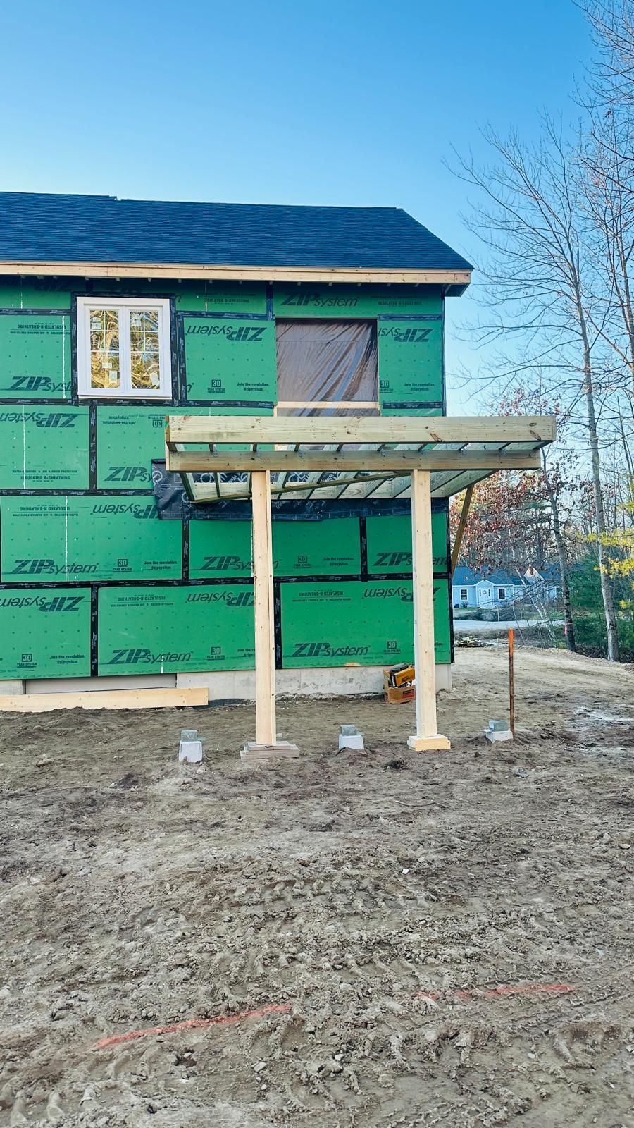 A house under construction with a pergola in front of it.