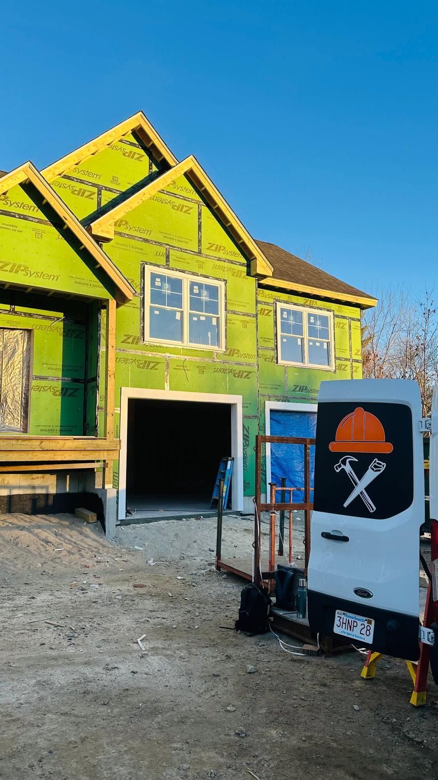 A white van is parked in front of a green house under construction.
