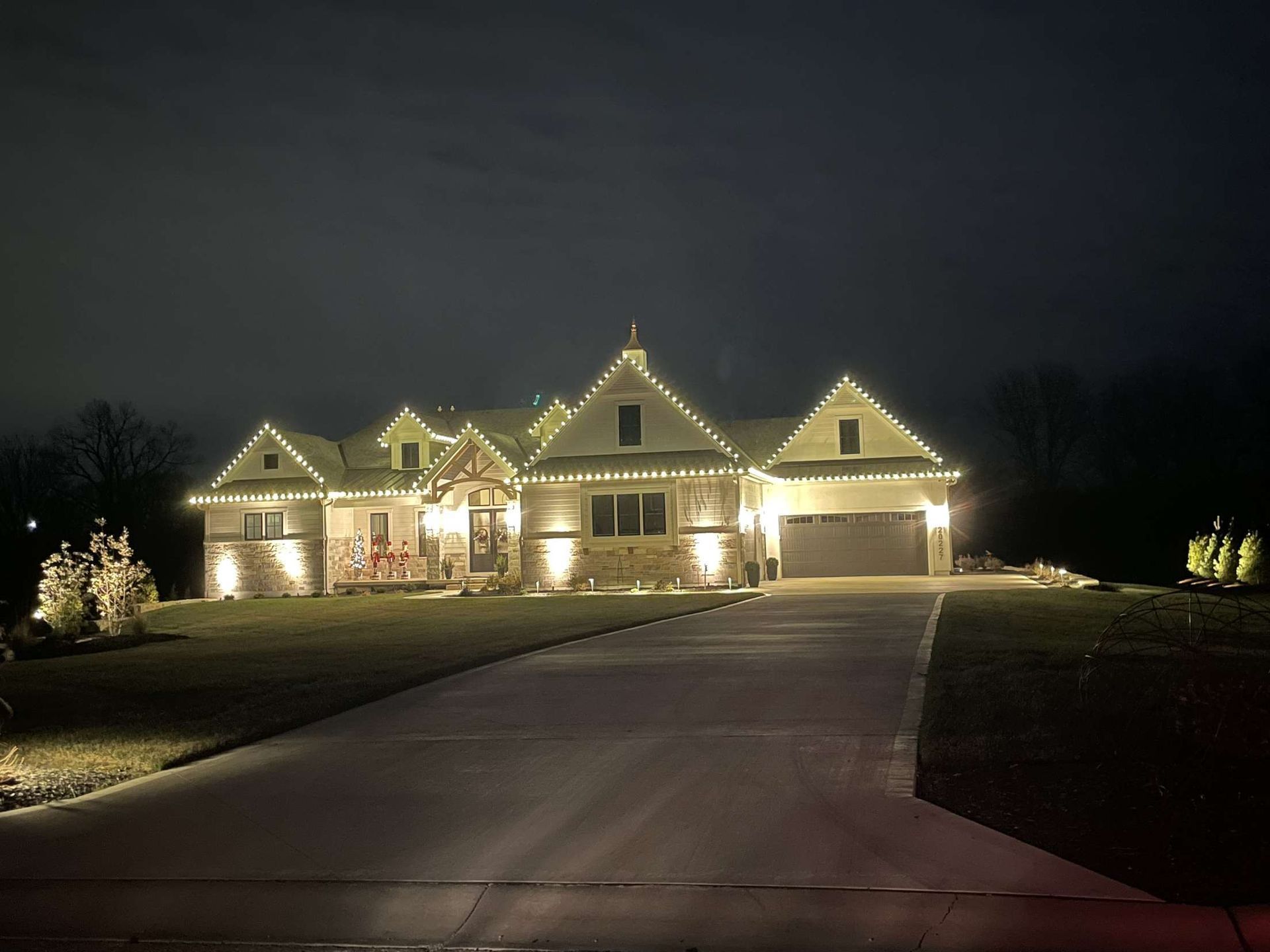A house illuminated with white lights, festive for the holidays, on a dark night.