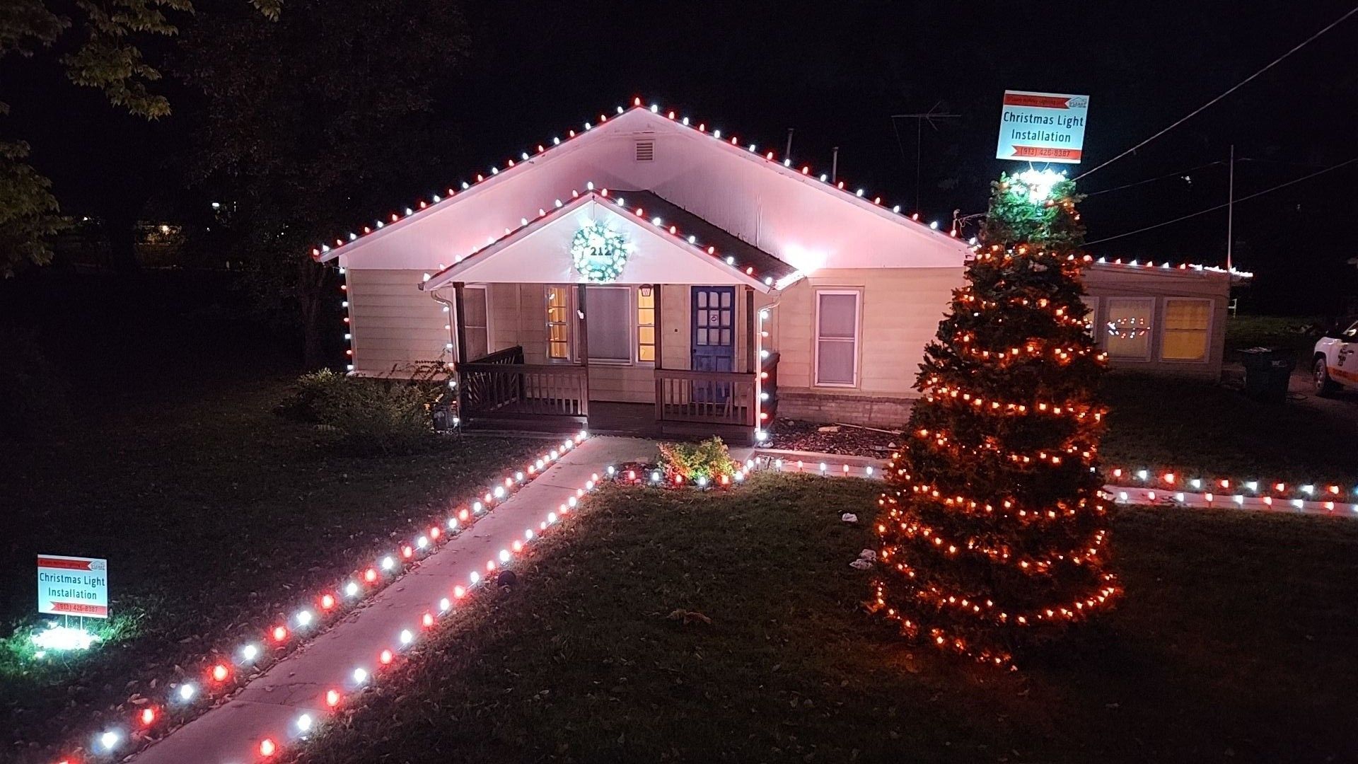 House decorated with Christmas lights; red and white lights outline the roof and pathway.