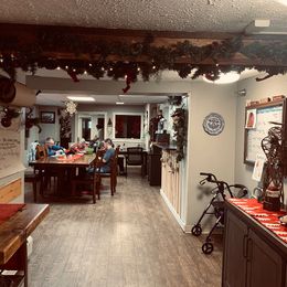 A group of people are sitting at tables in a room decorated for christmas