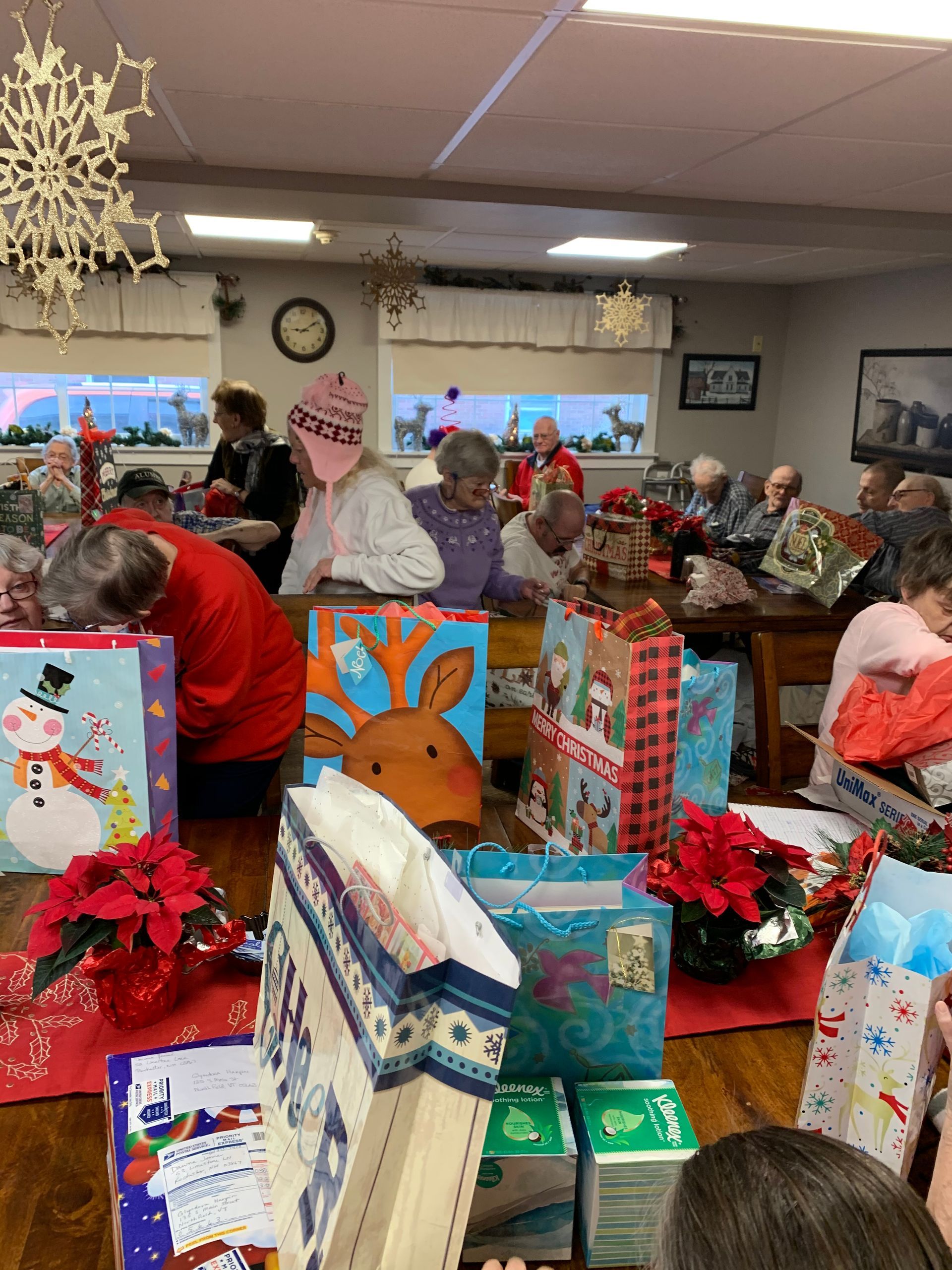 A group of people are sitting around a table filled with christmas presents.