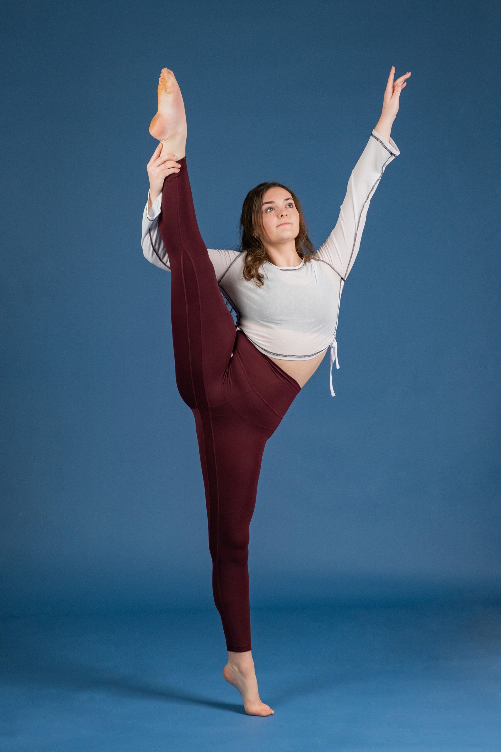 A young woman is doing a split on a blue background.