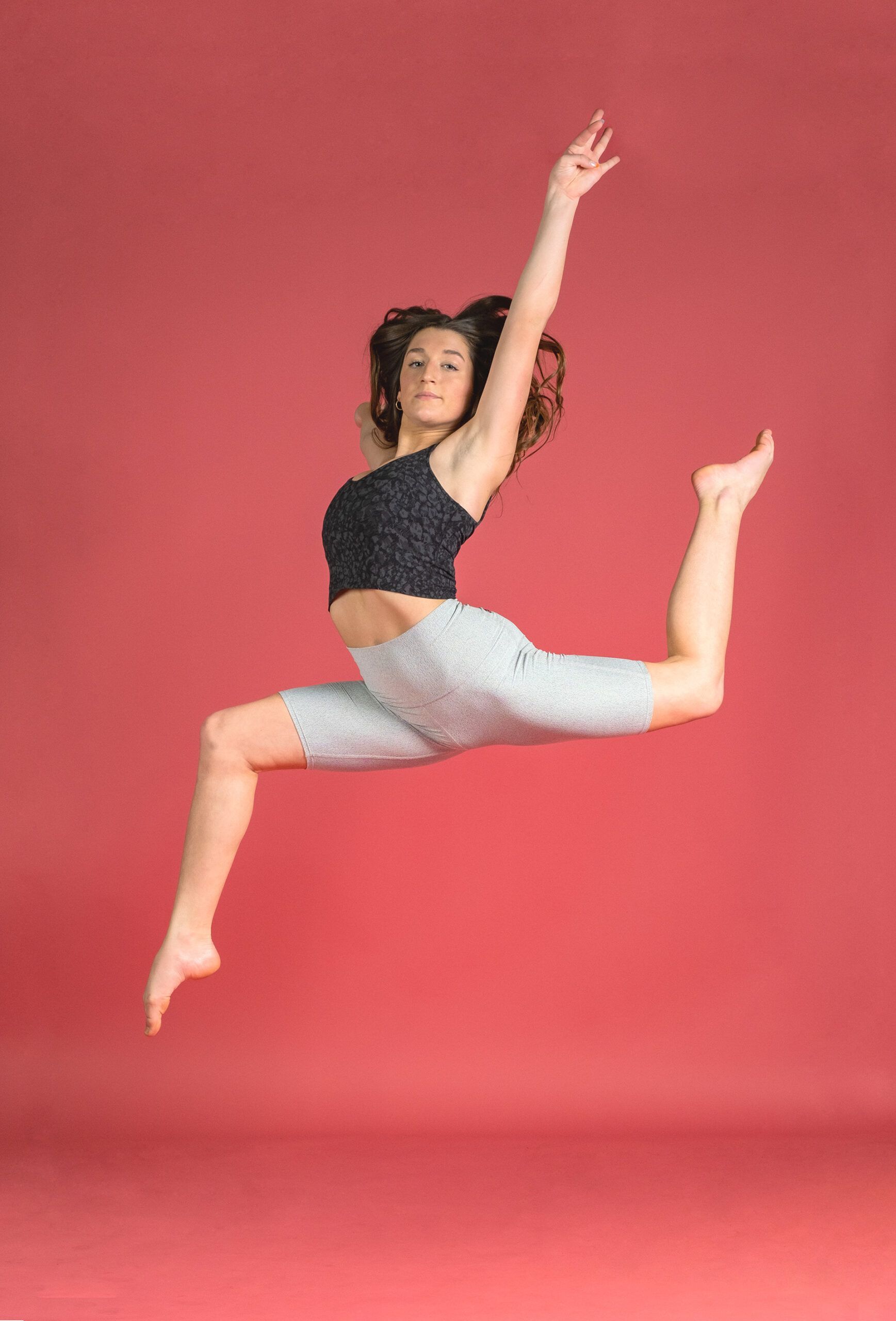A woman is jumping in the air in front of a red background.