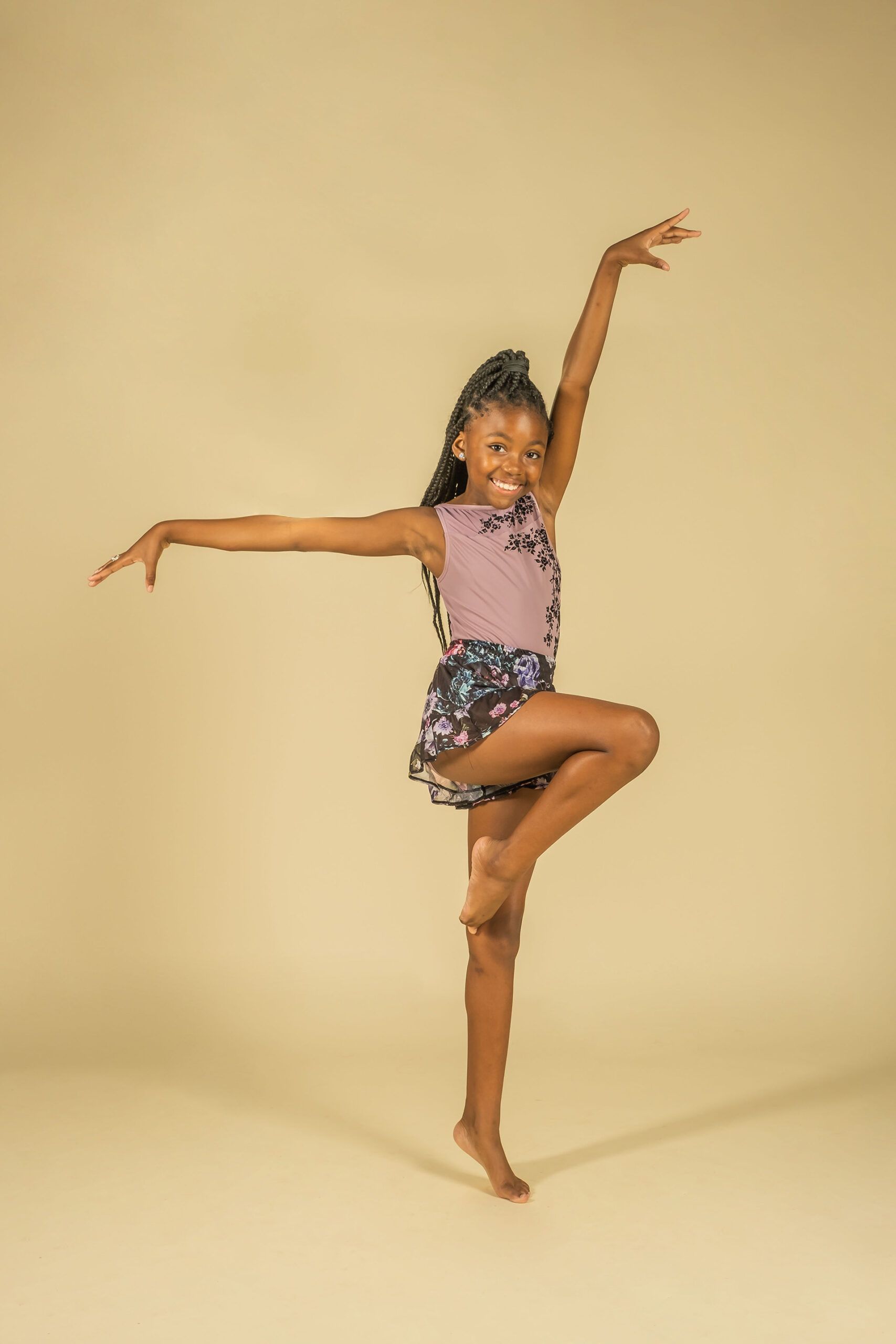 A young girl is standing on one leg with her arms outstretched.