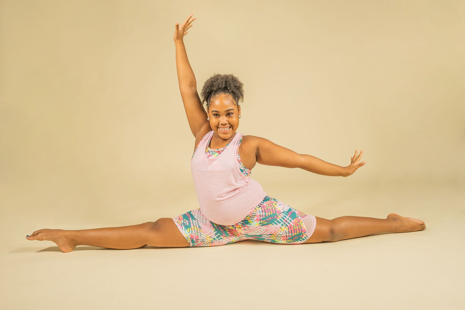 A young girl is doing a split on the floor.