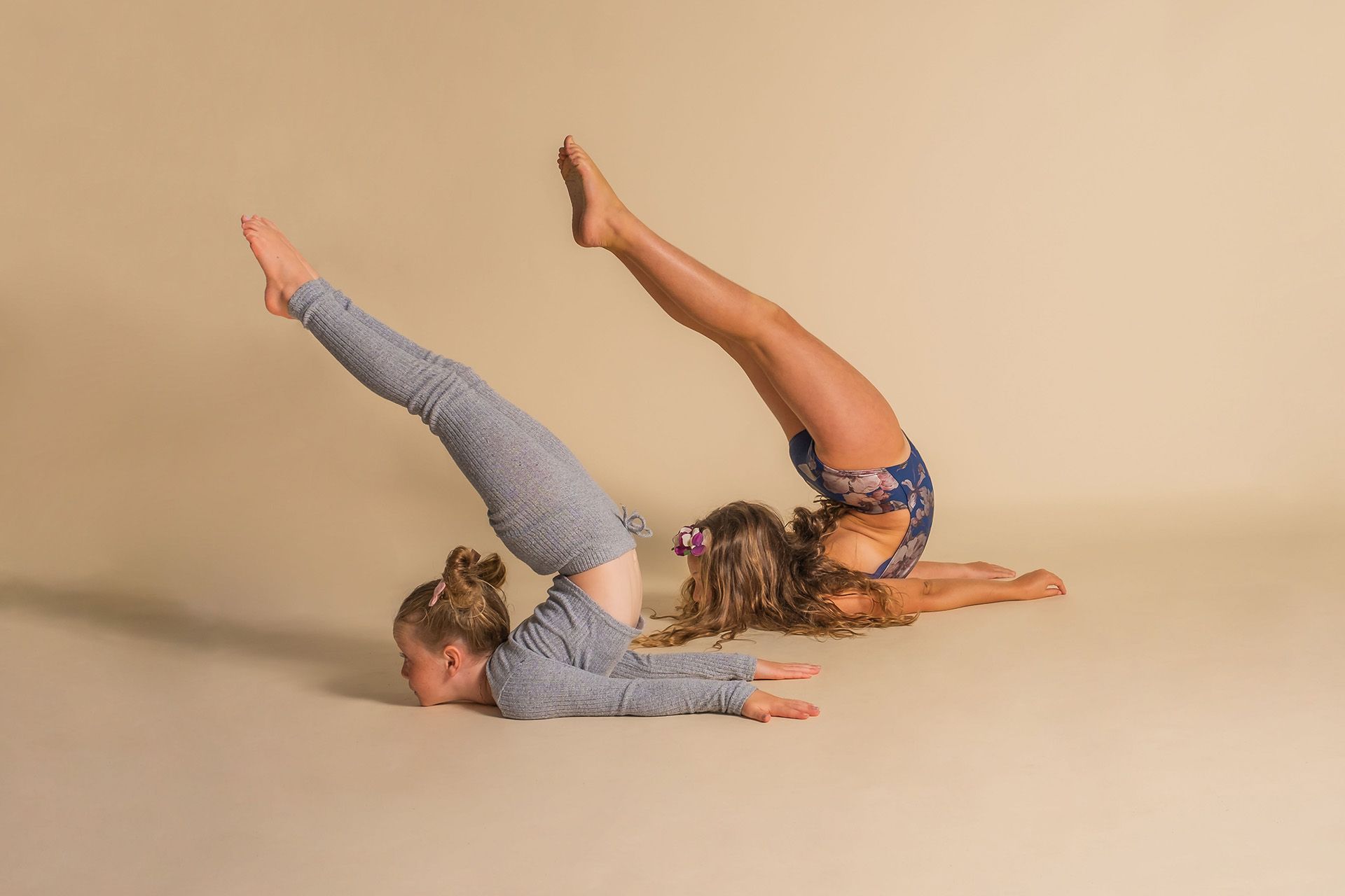 Two young girls are doing yoga exercises on the floor.