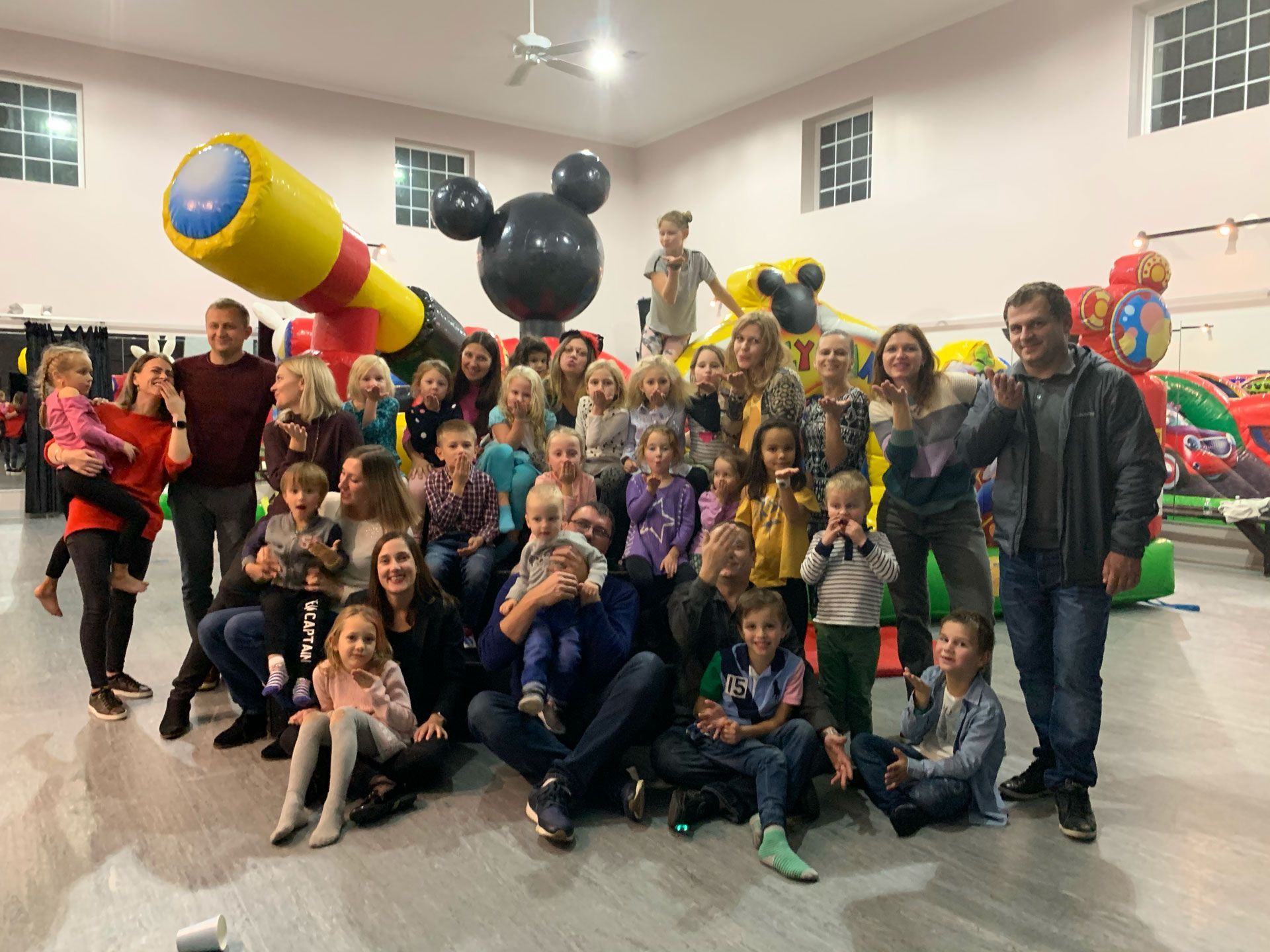 A large group of people are posing for a picture in front of a bouncy house.