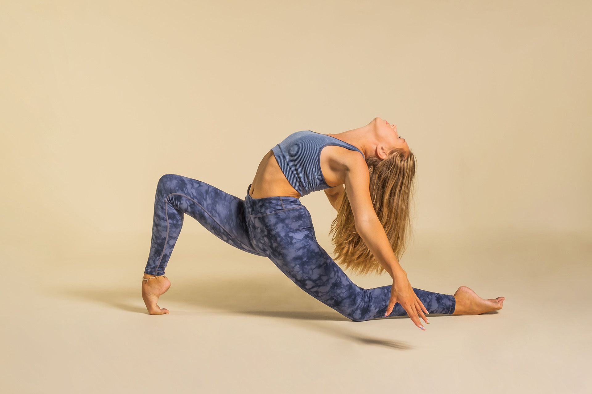 A woman is doing a yoga pose on a beige background.