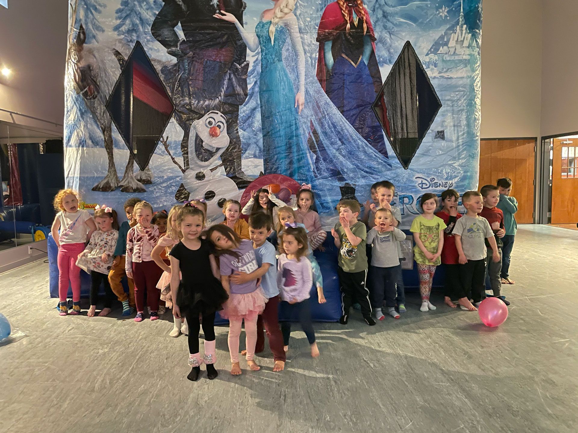 A group of children are posing for a picture in front of a frozen poster.