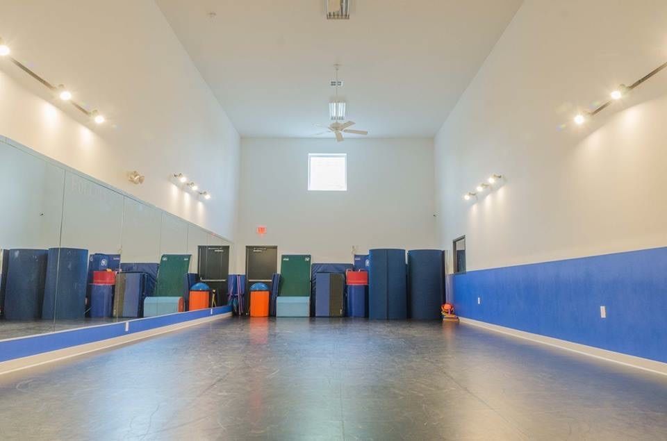 a large dance studio with a lot of mats and mirrors