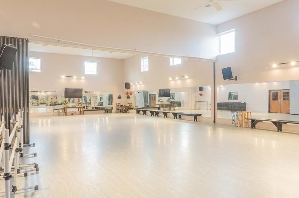 a large empty dance studio with a large dance floor and mirrors