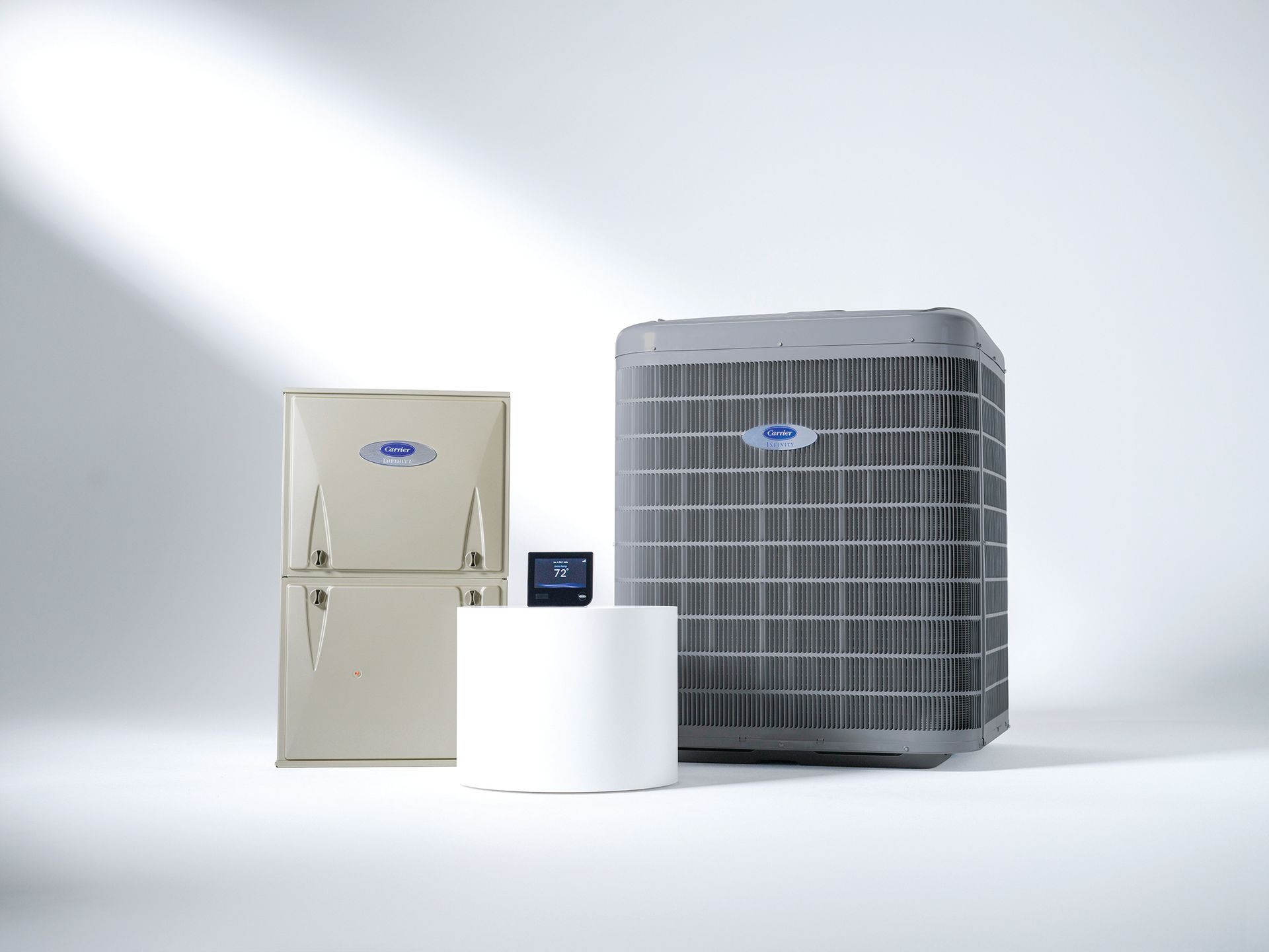 Carrier HVAC system components displayed on a white surface: furnace, outdoor unit, humidifier, and thermostat.