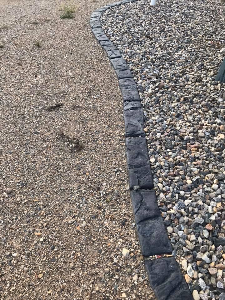Gravel path bordered by dark, textured edging. On the left is tan gravel, on the right is gray gravel.