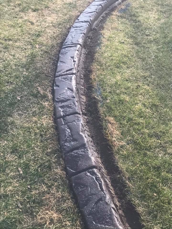 Dark gray, decorative concrete curbing bordering a grassy area.