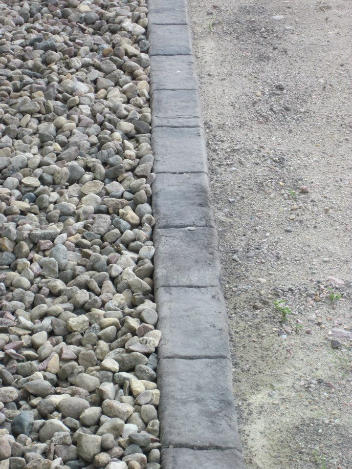 Gravel border separating a stone-covered area from a sandy, dirt surface.