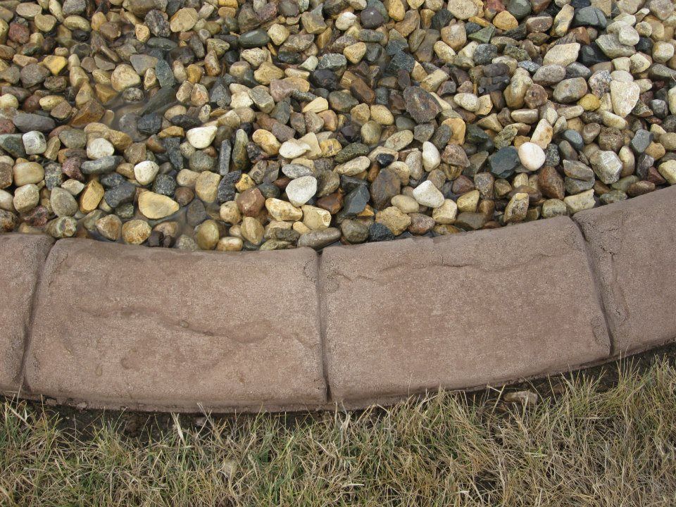 Stone-edged landscaping border with gravel topping and grass below.