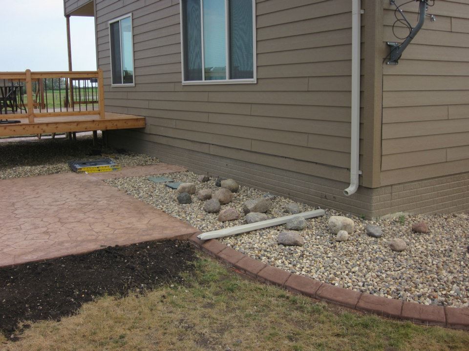House exterior with brown siding, a deck, and a gravel bed with rocks along the foundation.