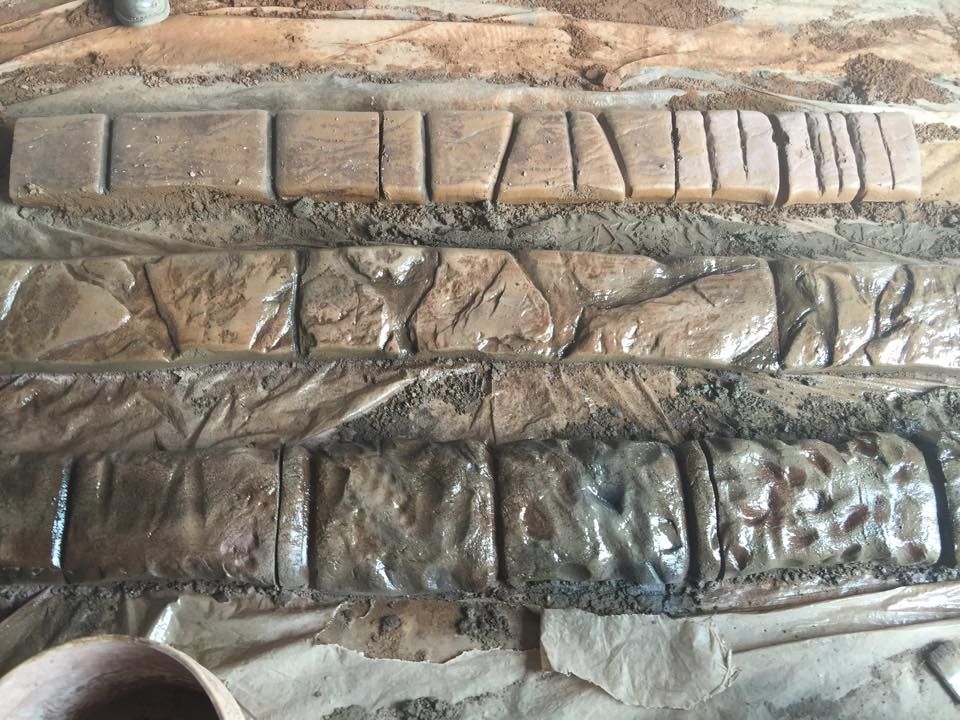 Textured concrete panels in various patterns, including brick and stone, displayed on a surface.