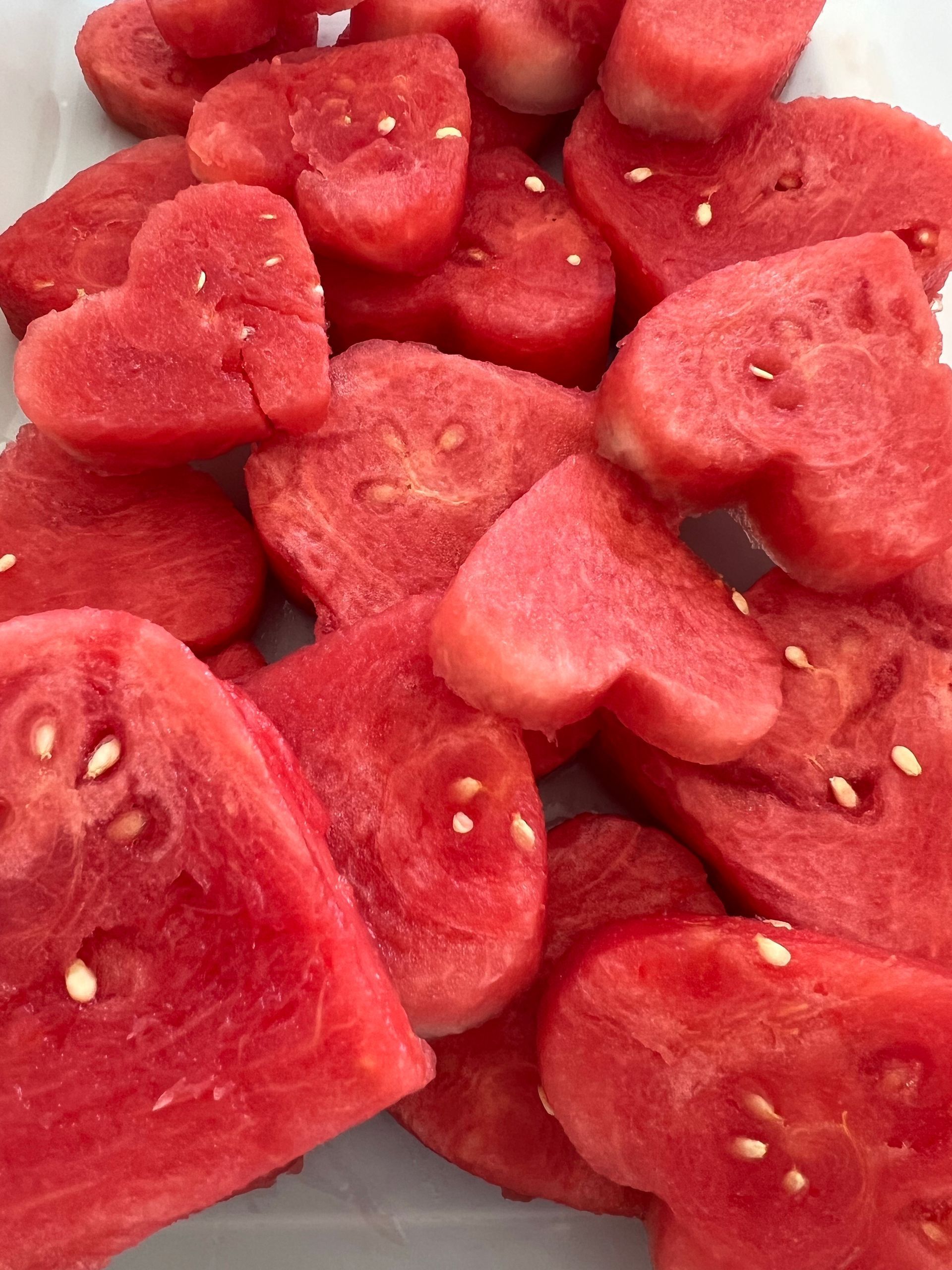 Close-up of sliced red watermelon pieces with visible seeds, piled together