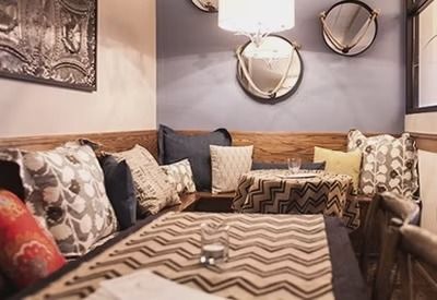 Cozy booth seating with patterned cushions, zigzag table runner, and wall decor in a warm-toned lounge