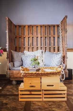 Rustic wooden bench with gray pillows and a woven basket, set against a pallet-style backdrop.