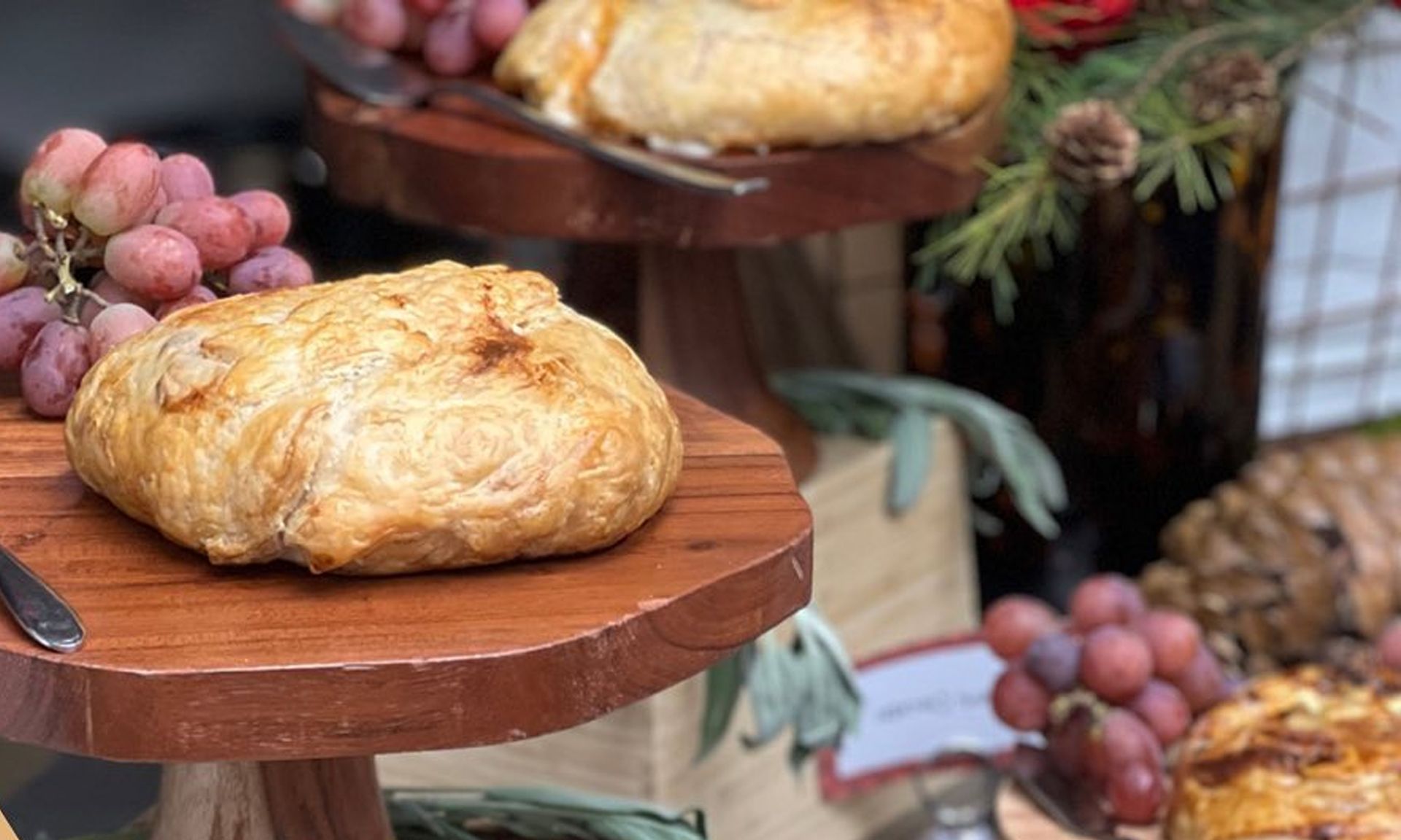 Pastries on wooden stands with grapes and rustic decor at an outdoor market
