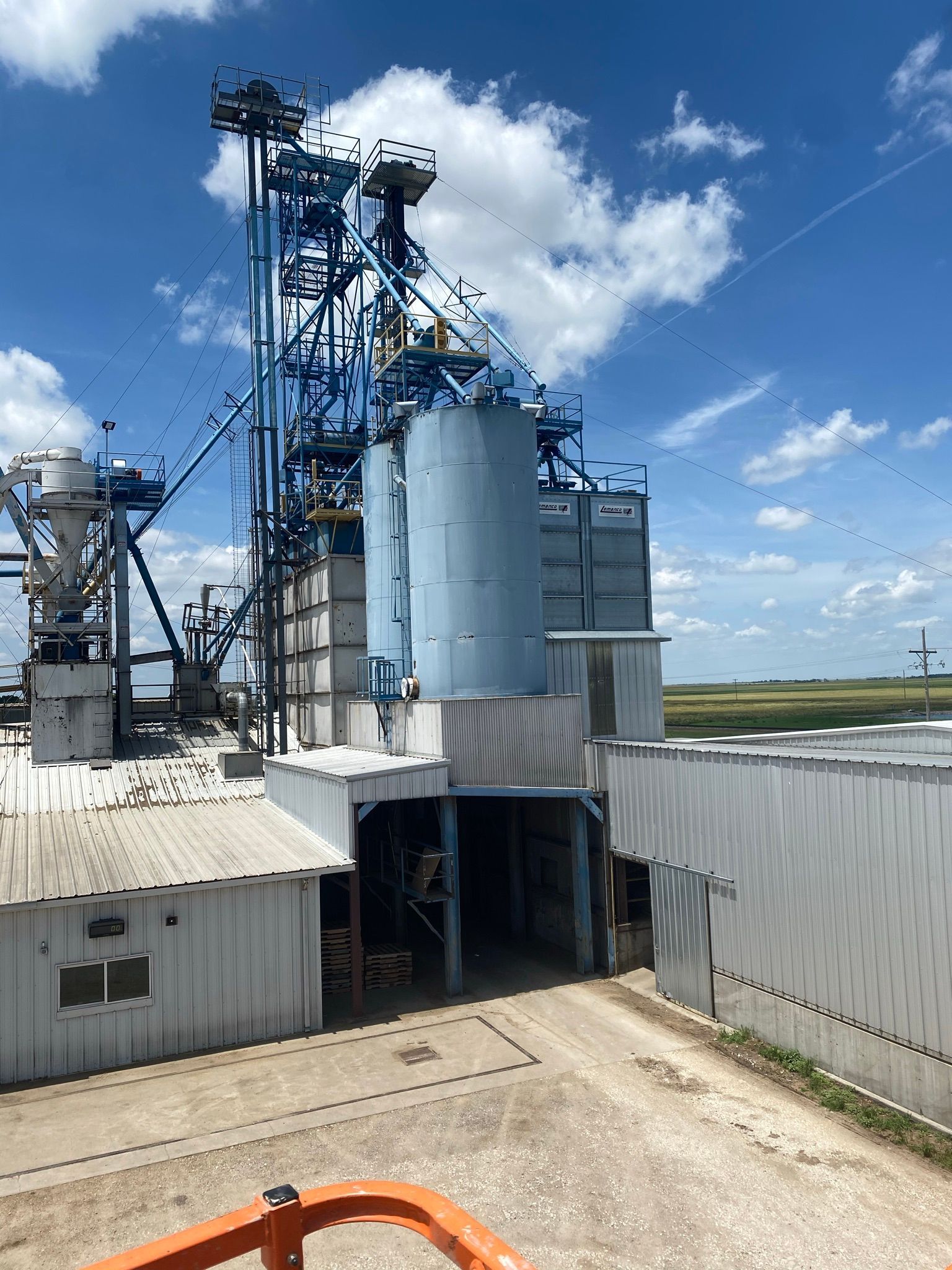 Blue grain elevator complex under a partly cloudy sky.