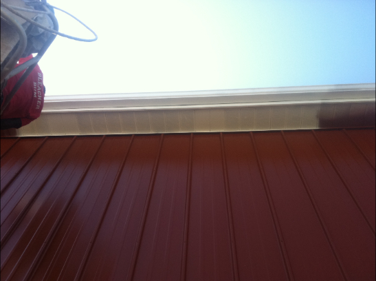 Red siding with tan trim and blue sky.