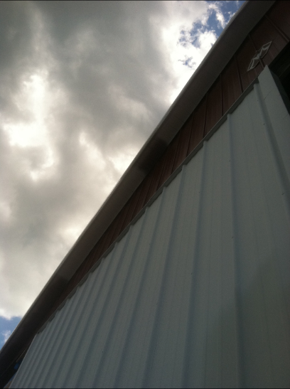 White building with corrugated siding under a cloudy sky.