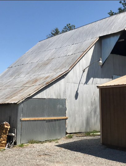 Galvanized metal barn under a clear blue sky.